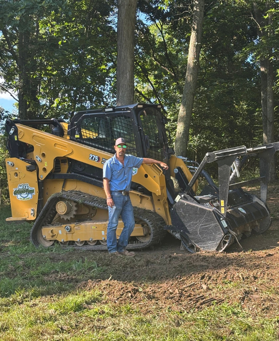 Jason Liddle standing with his track loader and forestry mulcher